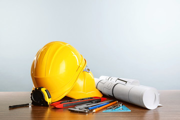 Construction blueprints with tools and helmets on light background