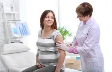 Doctor vaccinating young pregnant woman