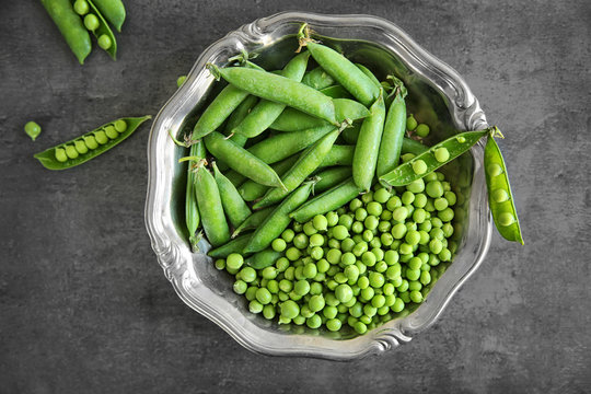 Fresh green peas in metal bowl on table