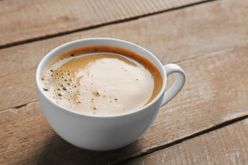 White cup of coffee on wooden background