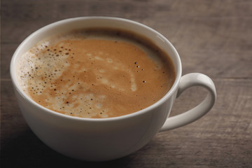 White cup of coffee on wooden background