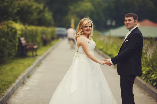 A wedding couple holds their hands together while walking along