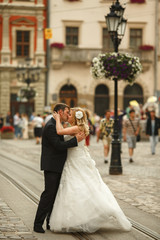 A passionate kiss of newlyweds standing on the tramways