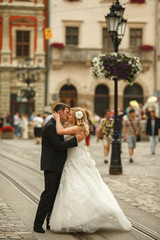 Naklejka premium A passionate kiss of newlyweds standing on the tramways