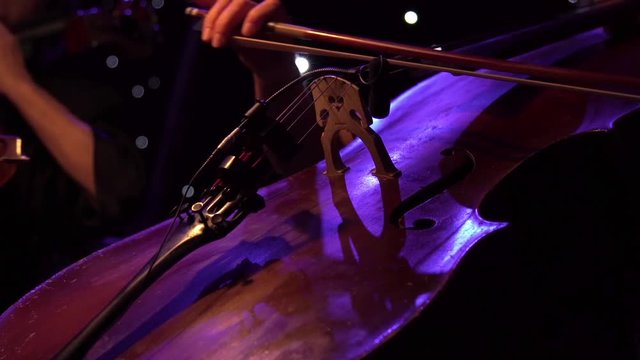 Concert, a woman musician hand playing the cello on stage, hand close up.