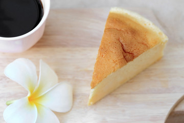 Pieces of Japanese style Cheesecake and cup of black coffee on w