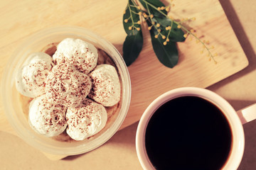 Banoffee cake in cup and black coffee, top view on wooden plate.