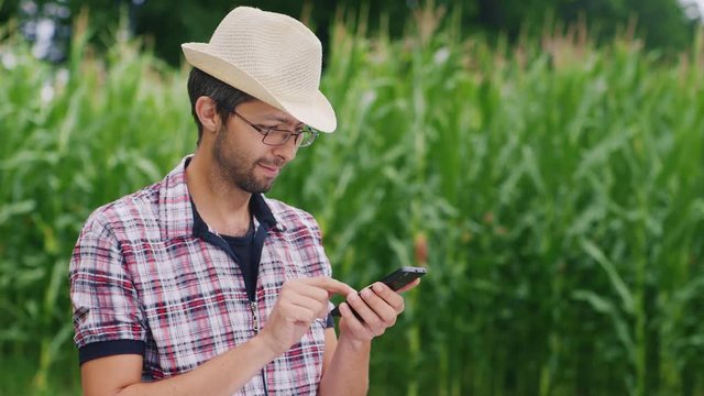 Sequence of 2 video: Portrait of attractive farmer in a hat and sunglasses. Use smartphones. Blurred back phono with space for titles