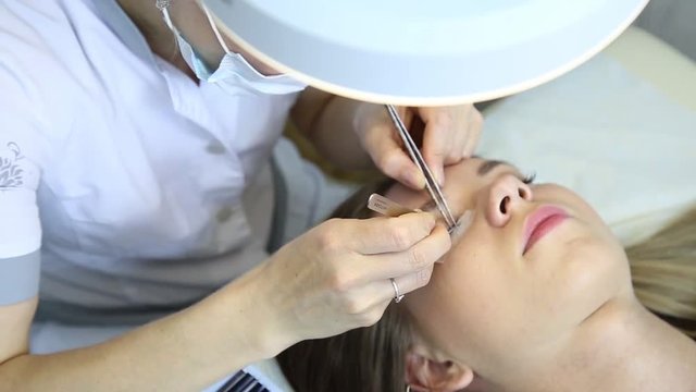 Beautiful young woman with eyelash extension. Woman eye with long eyelashes. Beautician eyelash extension for young woman in a beauty salon.