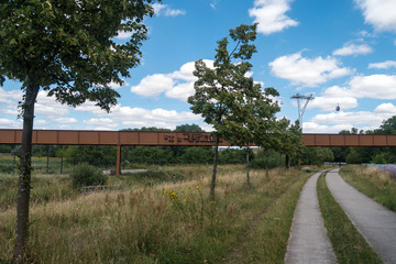 Fototapeta na wymiar Fuß- und Radweg im Wuhletal in Berlin - IGA 2017 - Im Hintergrund mit Fußgängerbrücke und Drahtseilbahn