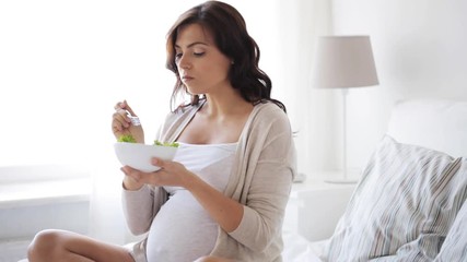 pregnant woman eating salad in bed at home 3 - Powered by Adobe
