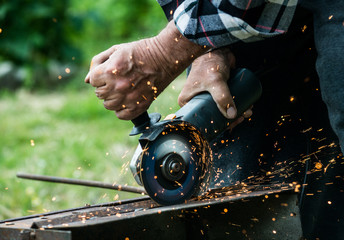Closeup of worker using a grinder on a metal plate