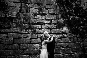 Bride hugs groom tenderly standing alone behind an old castle