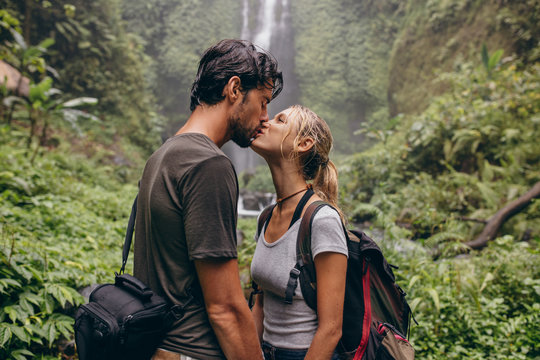 Couple in love kissing near a waterfall in forest