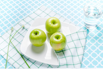 Fresh green apples in a dish on table.