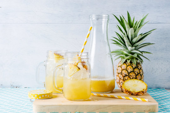 Pineapple slices and juice in glassware on wooden table