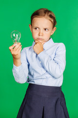 school girl in a school uniform with light bulb. Learning, idea and school concept. Image on green background.