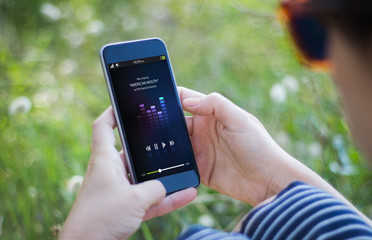 girl in grass holding her smartphone and listening music