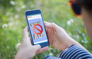 girl in grass holding her smartphone with ads blocker