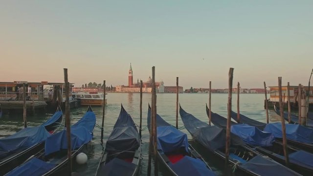 Parking gandolas on the Doge's palace embankment with the bell tower of the Saint Giorgio Maggiore church view.