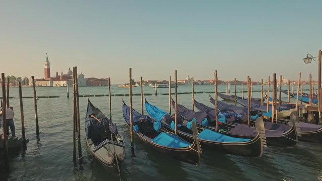 Parking gandolas on the Doge's palace embankment with the bell tower of the Saint Giorgio Maggiore church view.