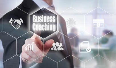A businessman selecting a Business Coaching Concept button on a hexagonal screen