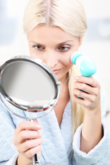 Oczyszczanie skóry twarzy. Kobieta myje skórę twarzy szczoteczką  - obrazy, fototapety, plakaty