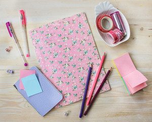 Girl back to school: pink notebook, pink pens, color pencils, pink washi tape on wood table. 
