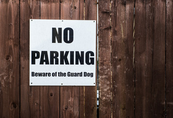 No parking and beware of guard dog sign on wooden gate