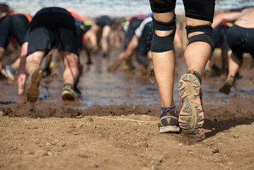 Mud race runners.Crawling,passing under a barbed wire obstacles during extreme obstacle race