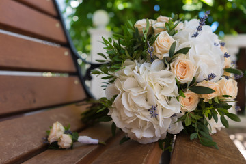 Beautiful bridal bouquet and boutonniere on a wooden bench