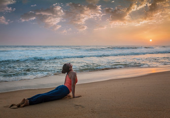 Fototapeta na wymiar Woman practices yoga asana Urdhva Mukha Svanasana at the beach
