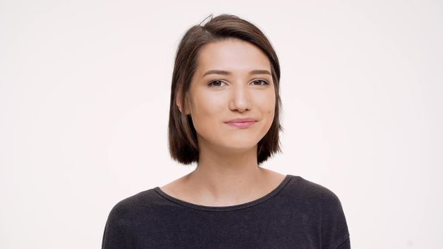Portrait of young pretty girl clicking finger and winking. Slow motion.