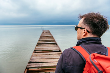Fototapeta premium Man standing on a river dock and looking sideways