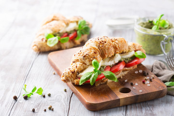 Wholegrain croissants with mozzarella, tomato and pesto, wooden table, selective focus