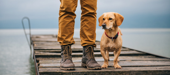 Man and his dog standing on dock - obrazy, fototapety, plakaty