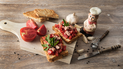 Vintage background with tomato and tuna bruschetta on rustic, old wood background