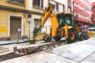 Yellow tractor works on the old street water-pipe