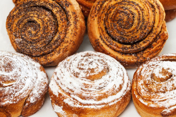 Sweet roll buns with shugar powder and poppy on table