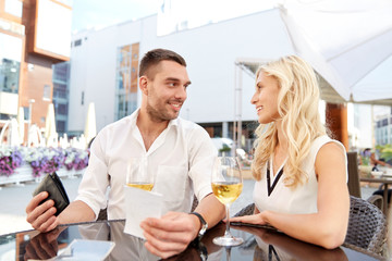 happy couple with wallet paying bill at restaurant
