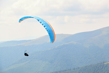 Paraglider is flying over the high mountains.