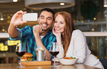 couple taking selfie by smartphone at restaurant