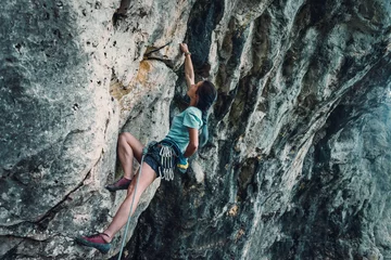 Gordijnen Woman climbing the rock wall © Alex Photo