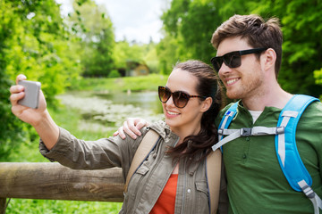 couple with backpacks taking selfie by smartphone