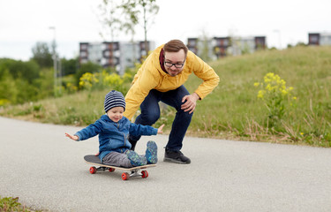 happy father and little son riding on skateboard