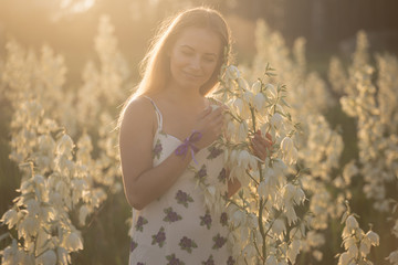 Princess. Young beautiful pretty woman posing in long dress against in the field with white flowers