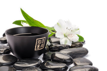 Fototapeta na wymiar Tea cup with stones and flower landscape composition