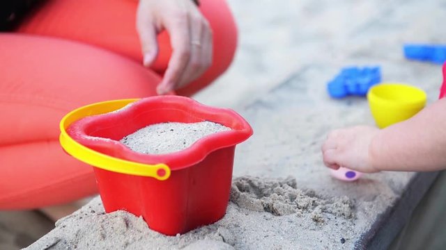 Toddler's hands playing with kinetic sand outdoors. Child making shapes. Lifestyle and summer concept.