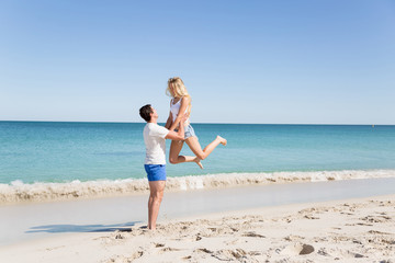 Fototapeta na wymiar Happy couple jumping on beach vacations