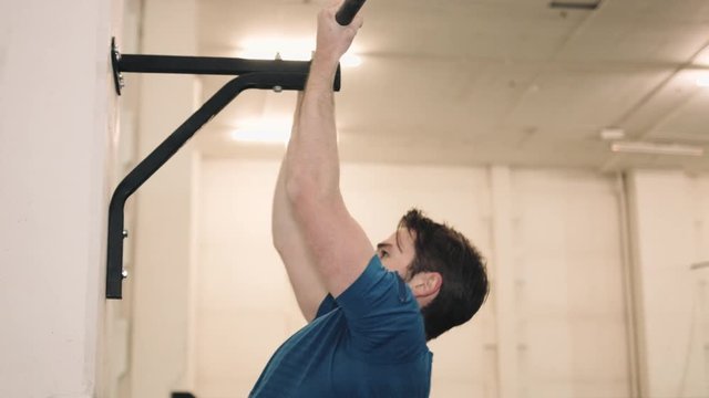 Young man lifting heavy barrel in bootcamp